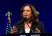 Woman speaking behind a podium with blue backdrop.