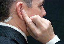 Man wearing an earpiece, touching his ear.