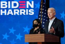 Two people speaking at a "Biden Harris" event.