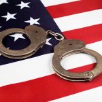 Handcuffs on the United States flag background.