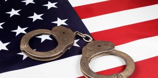 Handcuffs on the United States flag background.