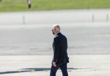 Man walking on pavement wearing a mask.