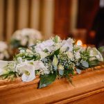 Flower arrangement on a wooden casket at a funeral.