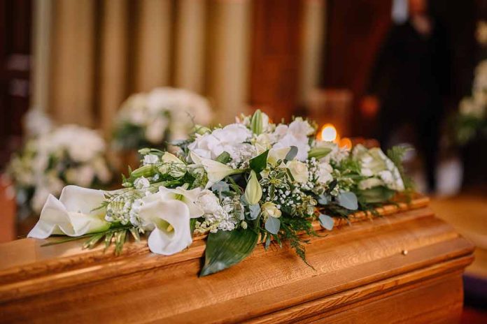 Flower arrangement on a wooden casket at a funeral.