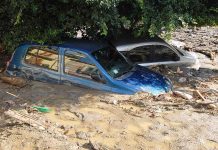 Two cars submerged in muddy floodwaters.