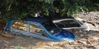 Two cars submerged in muddy floodwaters.