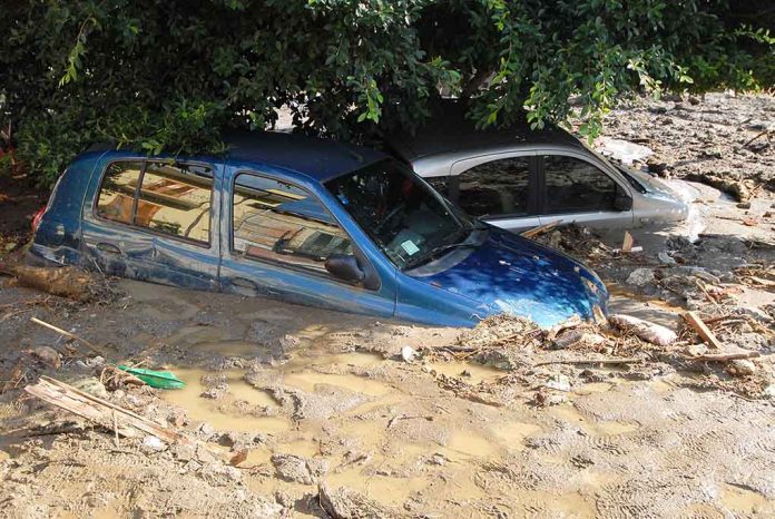 Two cars submerged in muddy floodwaters.