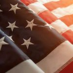 Close-up of American flag with sunlit background.