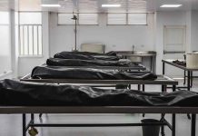 Covered bodies on metal tables in a morgue.