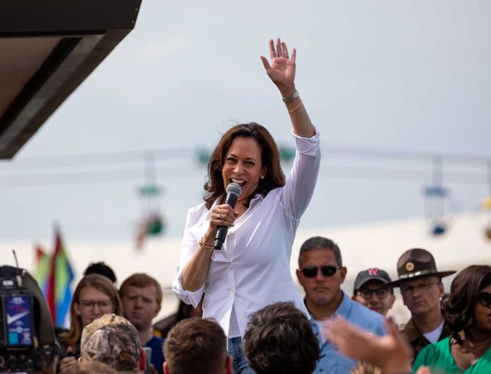 Woman speaking at outdoor event with raised hand.