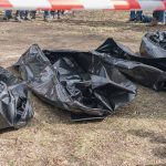 Three black body bags on the ground.