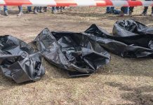 Three black body bags on the ground.