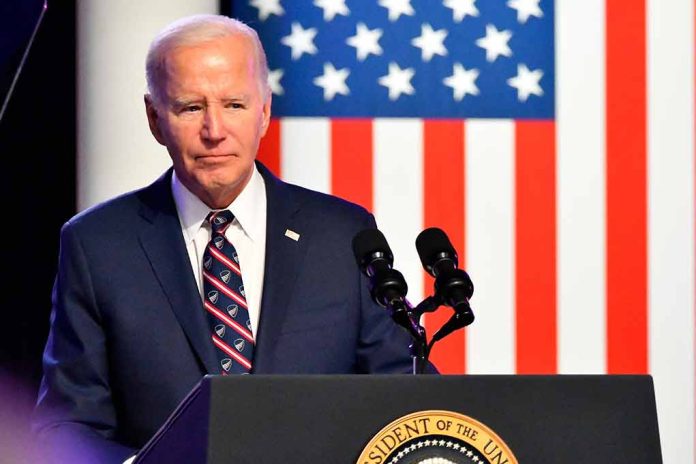 Man in suit speaking at podium with American flag backdrop.