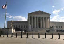 Supreme Court building with flag and people outside.