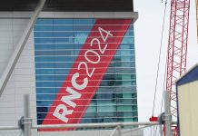 Building with "RNC 2024" sign, red construction cranes.