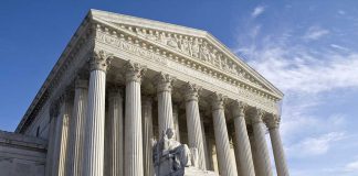 Supreme Court building with columns and statue in front.