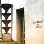 Department of Justice building exterior with column and sign.