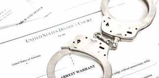 Handcuffs on top of an arrest warrant document.