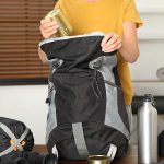 Person packing backpack with canned food indoors