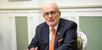 Man in suit talking at a table indoors.