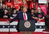 Politician speaking at rally with supporters behind him.