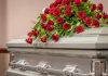 Casket adorned with a bouquet of red roses.