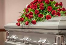 Casket adorned with a bouquet of red roses.