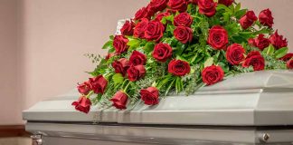 Casket adorned with a bouquet of red roses.