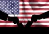 Silhouette handshake over United States flag background.