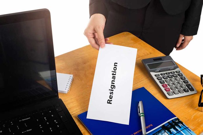 Hand holding a resignation letter on desk.