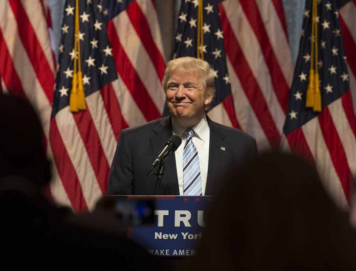 Person speaking at podium with American flags behind.