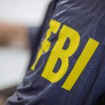 Person wearing jacket with "FBI" in yellow letters.