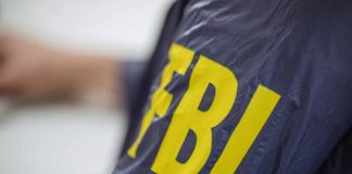 Person wearing jacket with "FBI" in yellow letters.