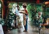 Artist painting on canvas in plantfilled studio