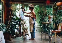 Artist painting on canvas in plantfilled studio