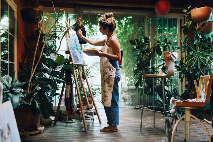 Artist painting on canvas in plantfilled studio