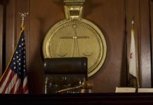 Judge's chair, gavel, flags, and scales of justice emblem.