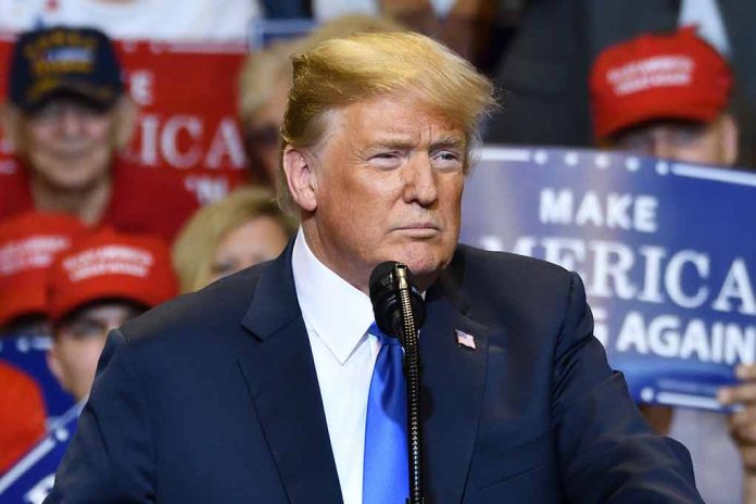 Person speaking at rally with "Make America Great Again" signs.