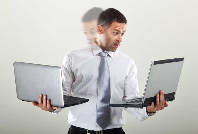 Man holding two laptops and looking surprised.