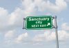 Green sign saying "Sanctuary City Next Exit."