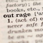 Close-up of the word "outrage" in a dictionary.