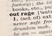 Close-up of the word "outrage" in a dictionary.