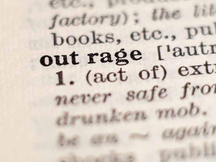 Close-up of the word "outrage" in a dictionary.