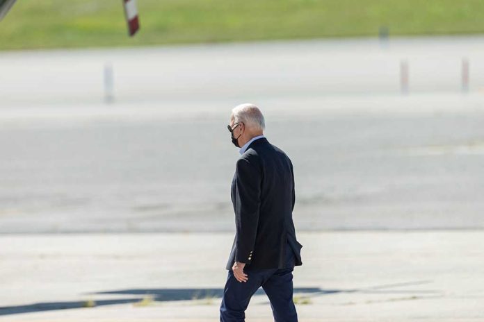 Person walking on tarmac wearing a black mask.