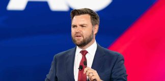 Man in suit speaking at a podium.