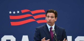 Man in suit speaking at a podium with microphone.