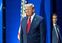 Man in suit next to American flag.