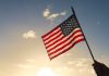 American flag waved against sunset sky.