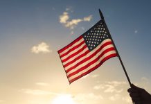 American flag waved against sunset sky.