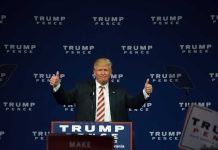 Person giving thumbs up at political event stage